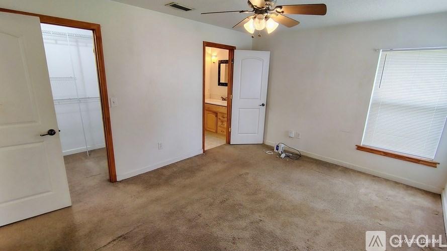 A room with a ceiling fan and a window with blinds.