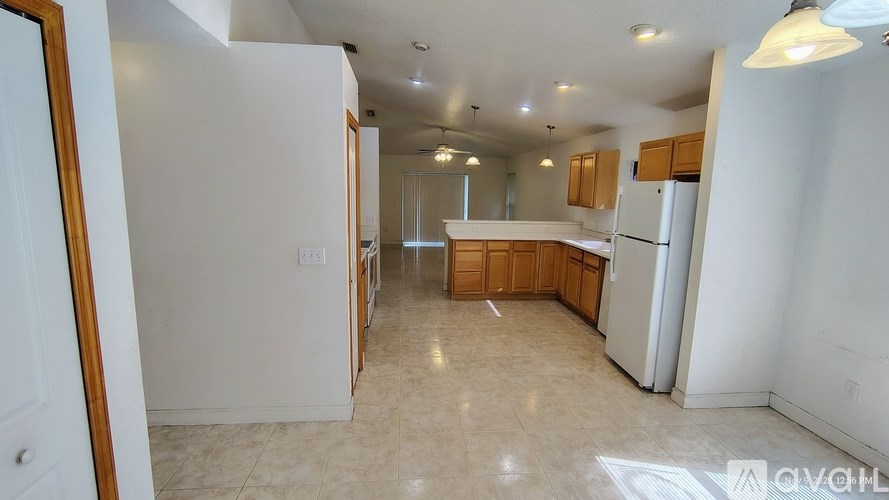 A kitchen with white walls and wooden cabinets.