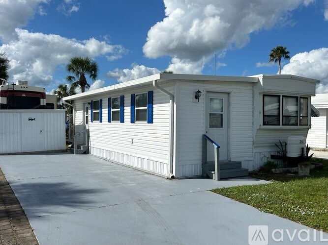 A white mobile home with a blue sky and clouds in the background.