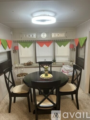 A dining room with a round table and chairs, a clock, and festive bunting.