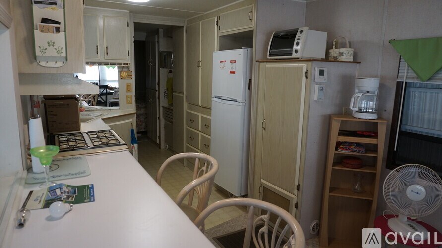 A kitchen with a white fridge, a white table, and a white chair.