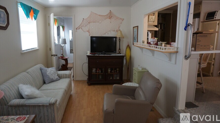 A living room with a grey couch, a brown leather chair, and a television.