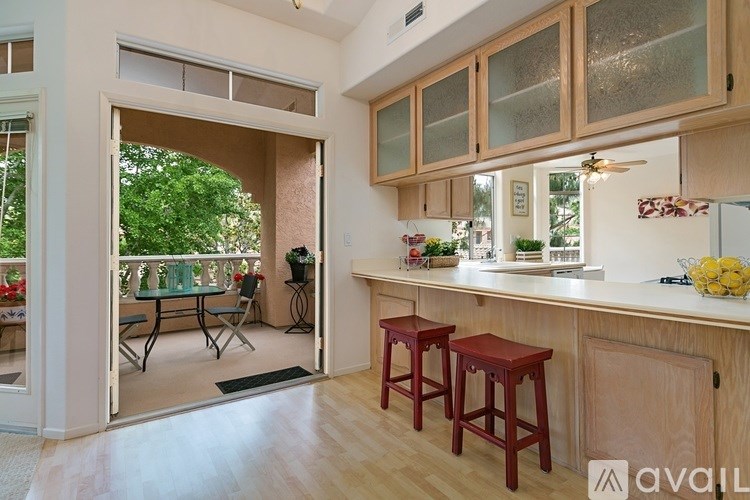 A kitchen with wooden cabinets and a bar area with stools.