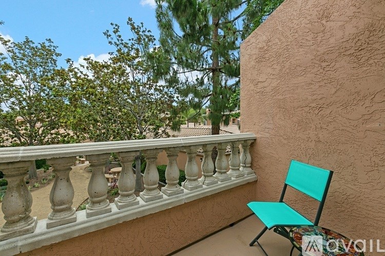 A balcony with a turquoise chair and a white railing.