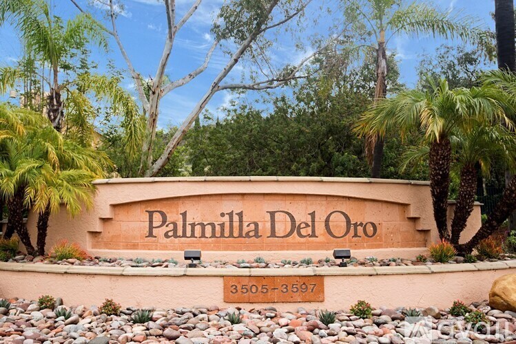 A sign that says Palmilla Del Oro in front of some trees.