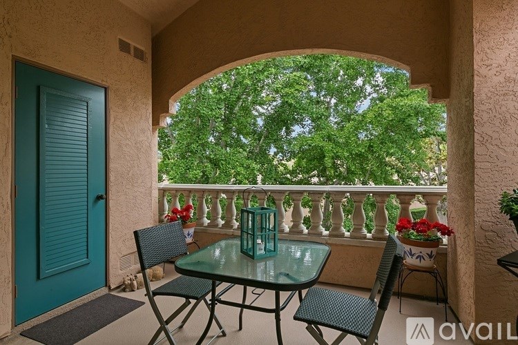A balcony with a table and chairs overlooking a green tree.