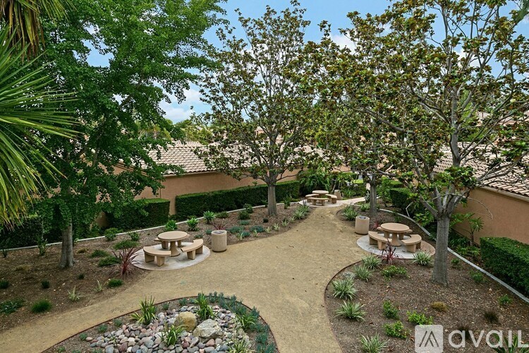 A backyard with a circular garden and a dining table surrounded by trees.