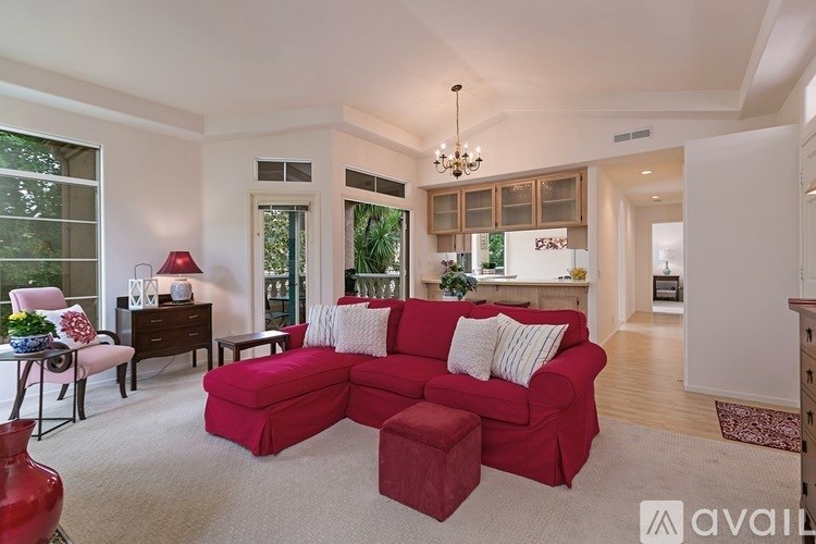 A living room with a red couch and a chandelier.