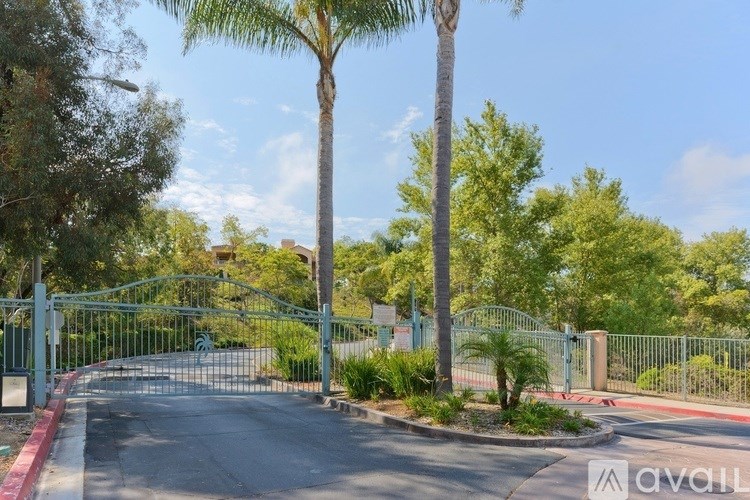 A gated entrance with a red curb and a tree in the background.