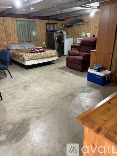 A room with a bed, chair, and a washing machine.