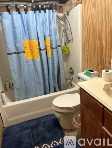 A blue shower curtain with yellow squares is hanging in a bathroom.