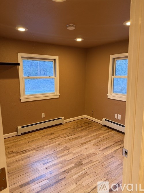 A room with wooden floors and two windows.