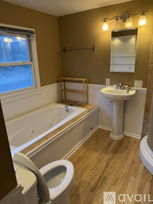 A bathroom with a tub, toilet, sink, and mirror.