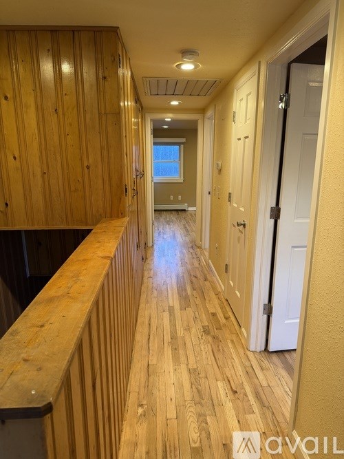 A long hallway with wooden floors and doors on both sides.