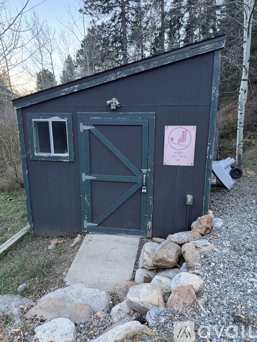 A small building with a green door and a sign on it.