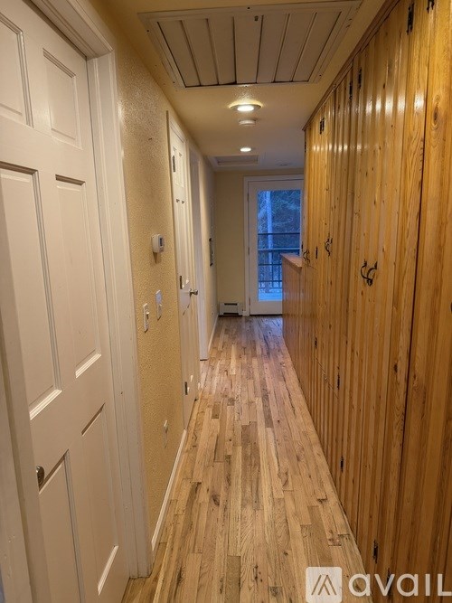 A long hallway with wood floors and white walls.