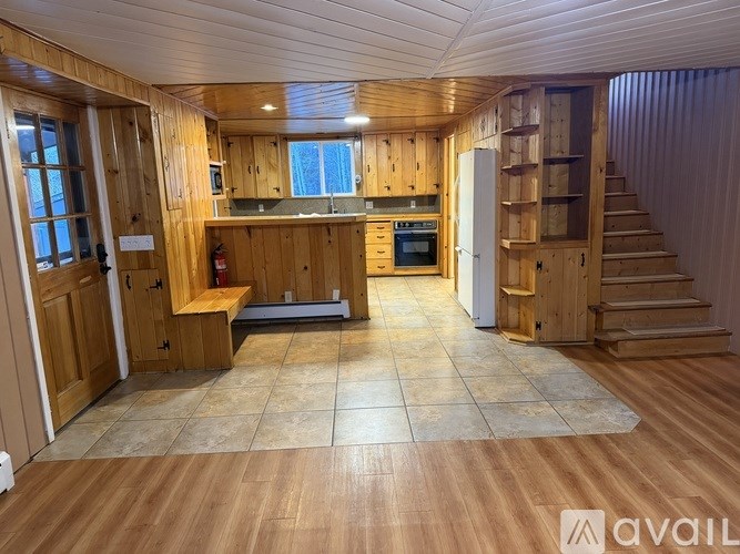 A wooden house interior with a staircase and a kitchen area.