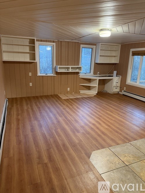 A room with wooden flooring and a desk with a window.