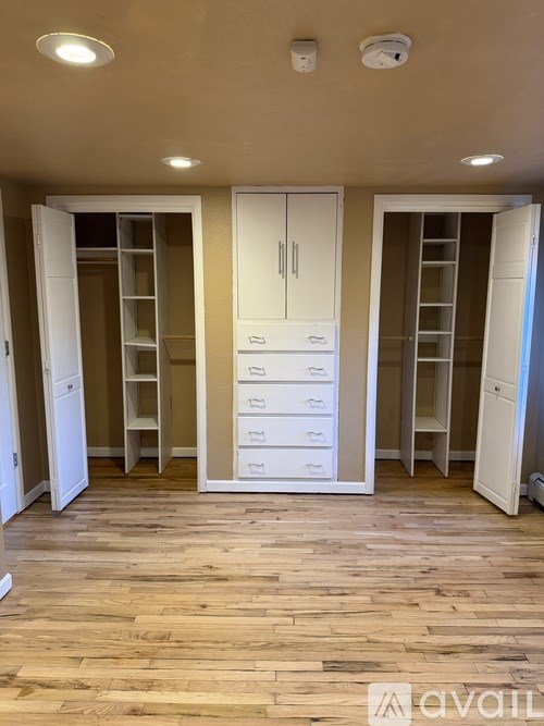 A room with wooden floors and white cabinets.
