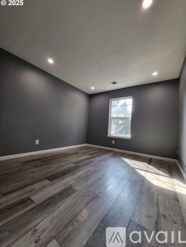 A room with wooden flooring and a window.