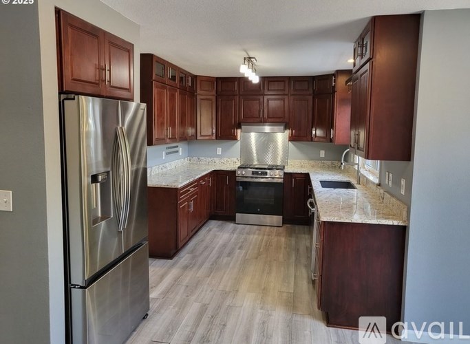 A kitchen with wooden cabinets and a stainless steel refrigerator.