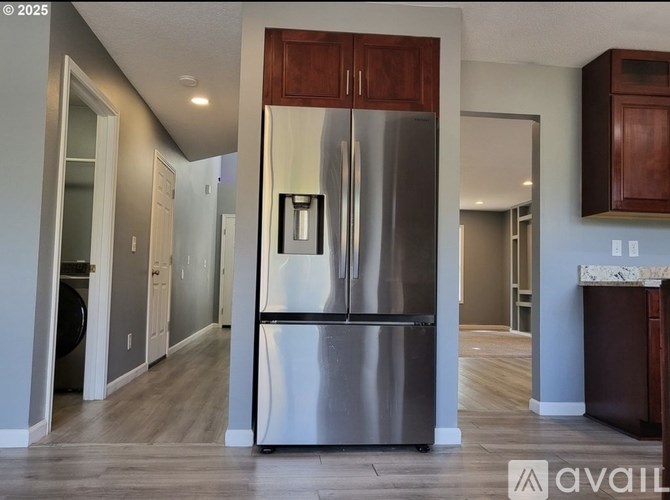 A modern kitchen with a stainless steel refrigerator and wooden cabinets.