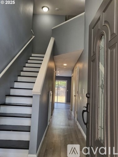A staircase with a white railing and black steps leads to a door.