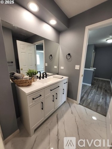 A bathroom with a sink, mirror, and cabinets.