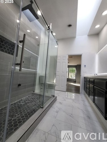 A modern bathroom with a walk-in shower and marble flooring.