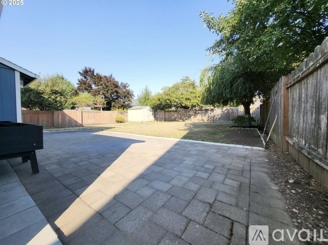 A backyard with a paved walkway and a wooden fence.