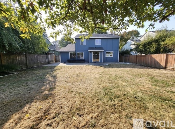 A blue house with a fenced backyard.