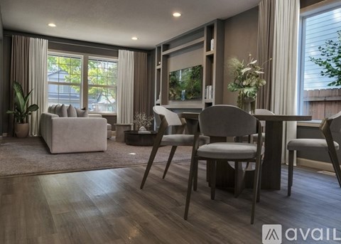 A modern living room with a grey sofa, two chairs and a television.