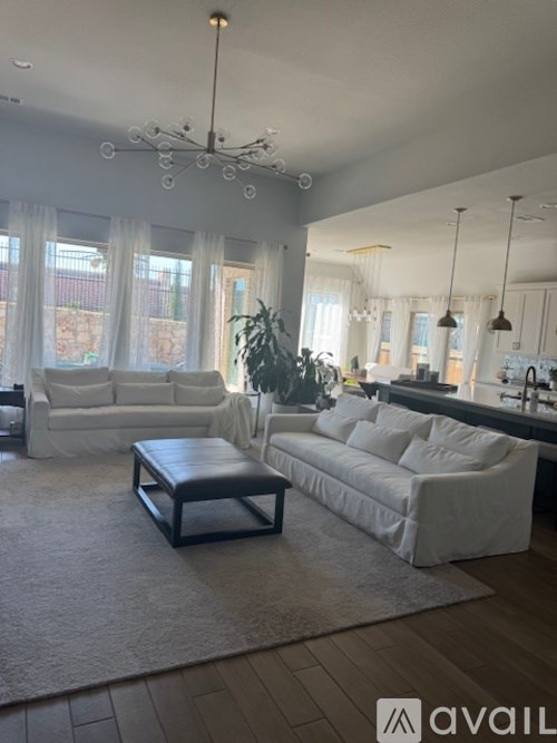 A living room with a white couch, a coffee table, and a chandelier.