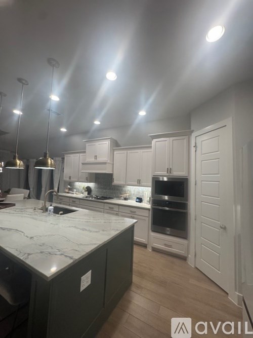 A kitchen with a marble countertop and white cabinets.