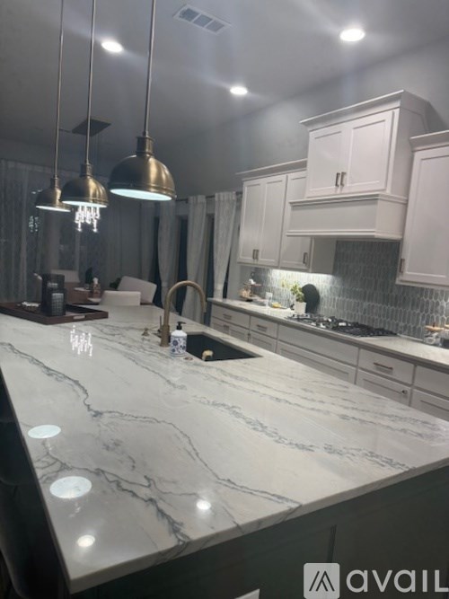 A kitchen with a marble countertop and pendant lights.