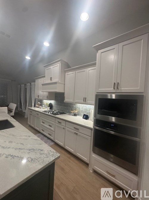 A kitchen with white cabinets and a marble countertop.