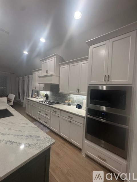 A kitchen with white cabinets and a marble countertop.