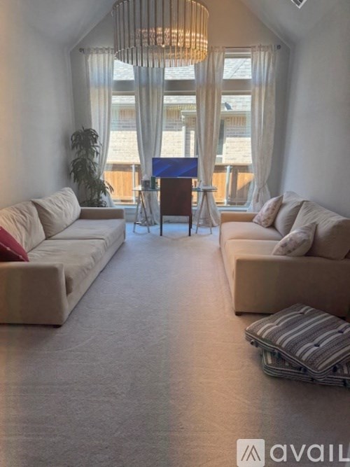 A living room with a large beige sofa, a wooden chair, and a striped ottoman.