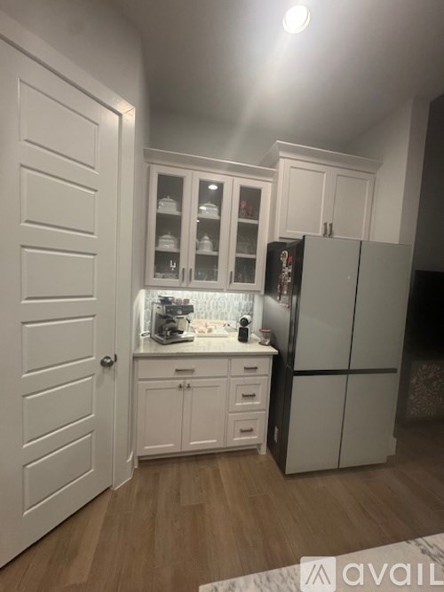 A kitchen with white cabinets and a black fridge.
