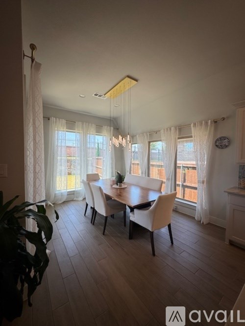 A dining room with a table set for four and a potted plant on the left.