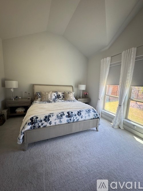 A bedroom with a large bed and a window with curtains.