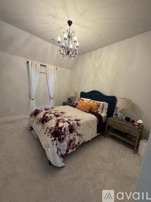 A bedroom with a bed, nightstand, and a chandelier.