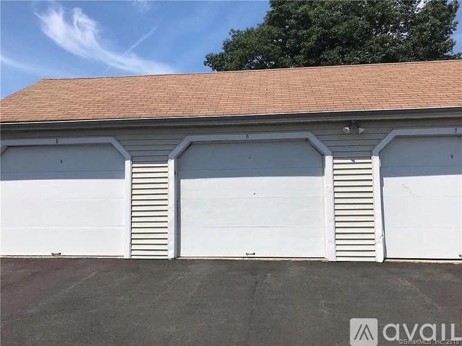 A building with two white garage doors and a red roof.