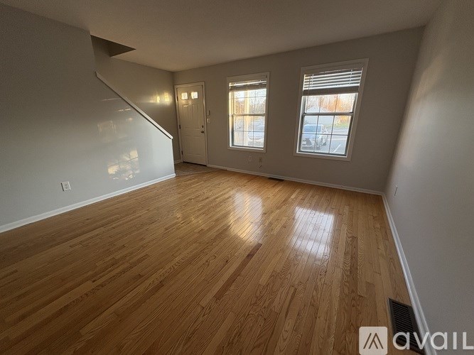 A room with wooden flooring and a staircase leading to another level.