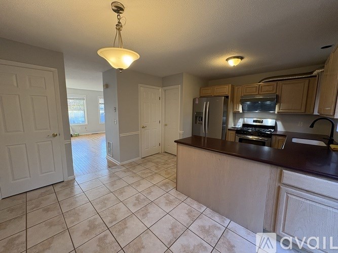 A kitchen with tile flooring and a hanging light fixture.