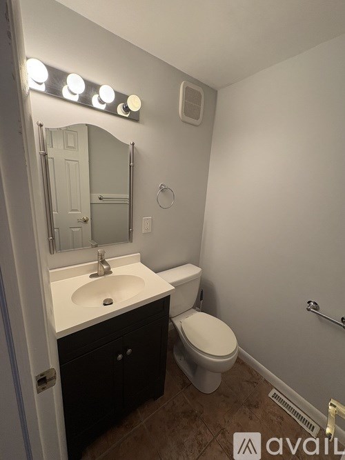A bathroom with a sink, toilet and mirror.