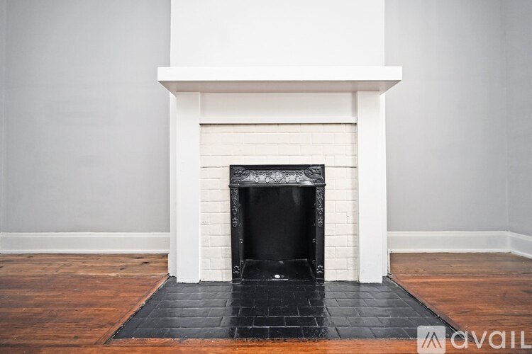 A fireplace with a black grate in a room with white walls.