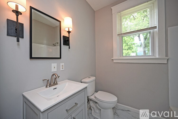 A bathroom with a white sink, toilet, and a mirror.