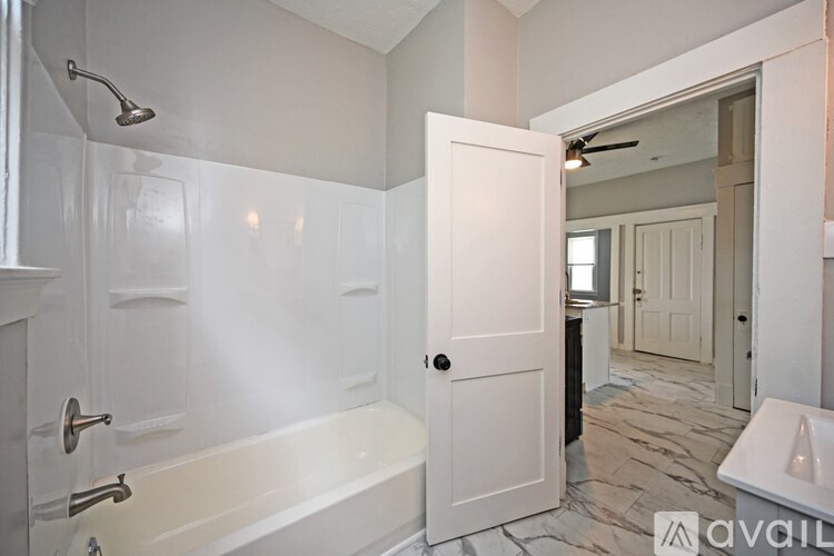A bathroom with a white tub and a shower head.
