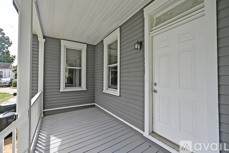 A porch with a white door and two windows.